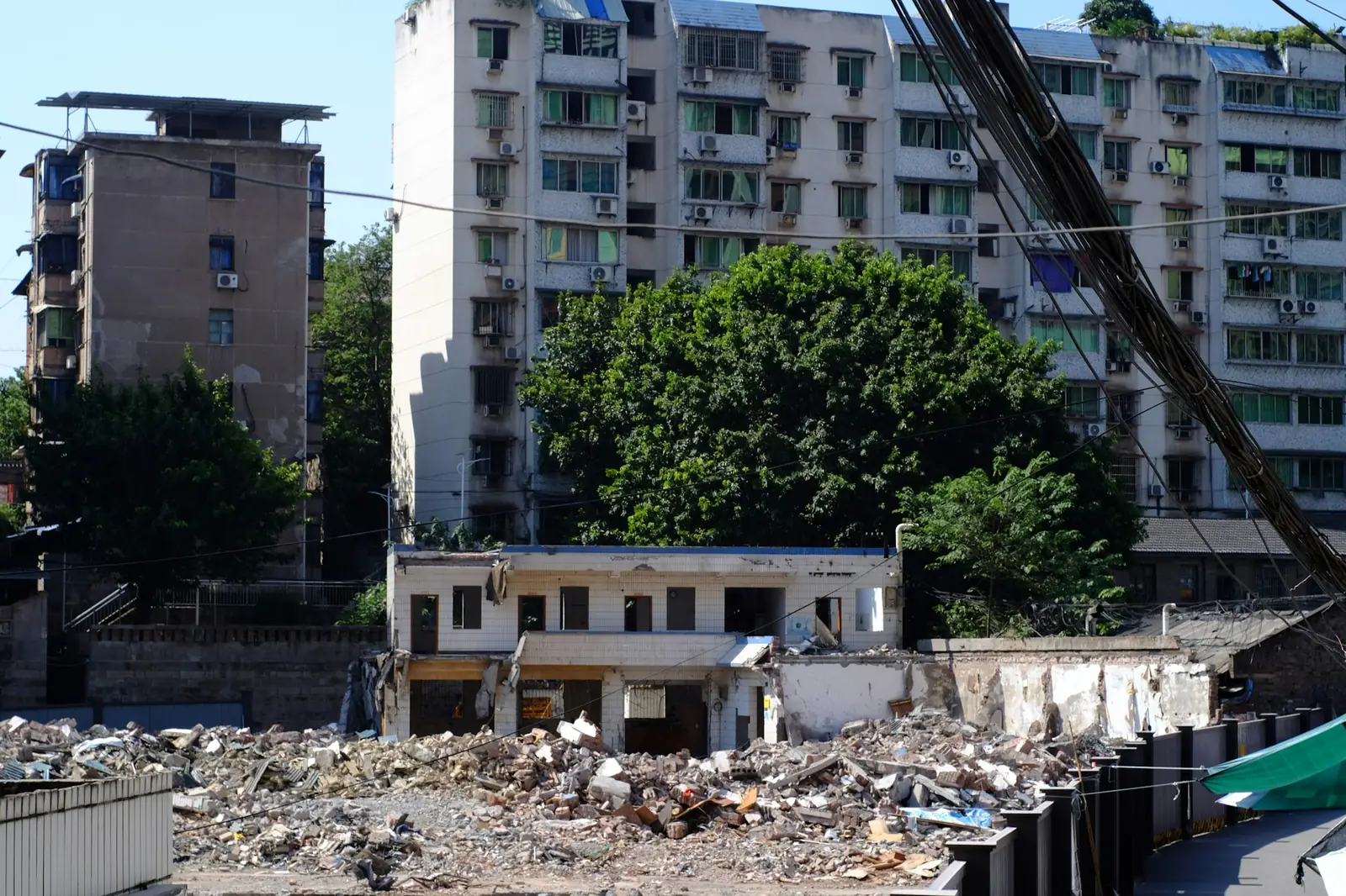 Demolished low-rise building with rubble in front of apartment towers